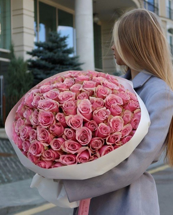 žena drží kyticu zo 100 ružových ruží