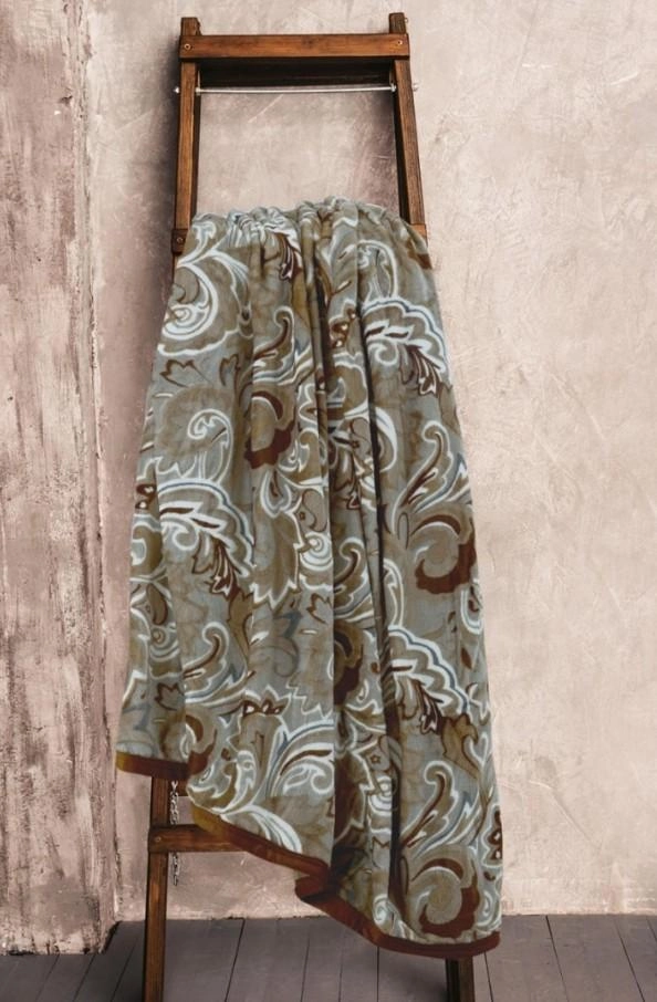 Mikroplyšová deka v hnedých farbách prevesená cez drevený sušič