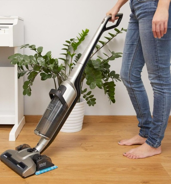 žena vysáva s bezkáblovým tyčovým vysávačom s mopom