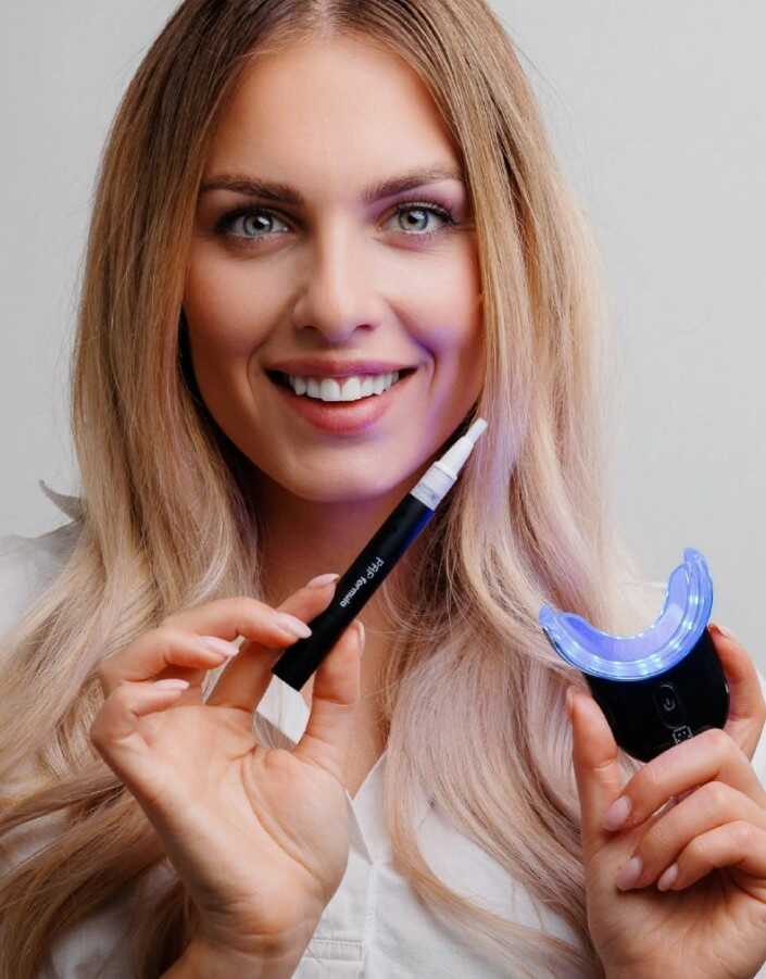 žena drží bieliace pero a LED zariadenie v rukách