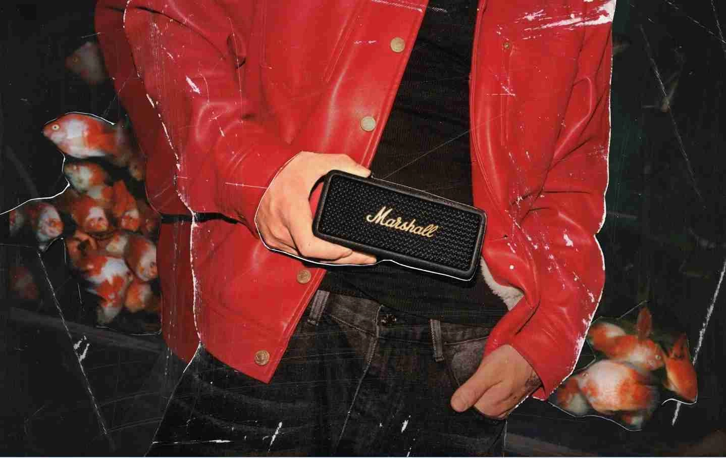 muž v červenej bunde drží v ruke reproduktor