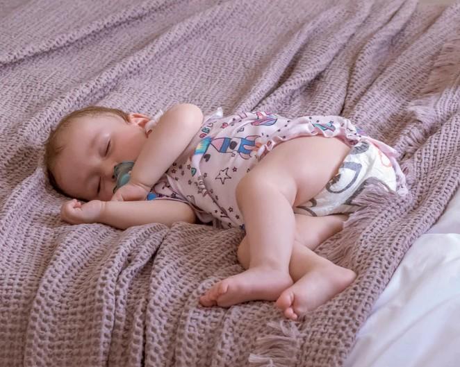 bábätko spí vo farebných plienkach na ružovej deke