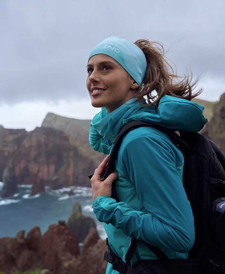 Žena na turistike s čelenkou a bundou v modrej farbe
