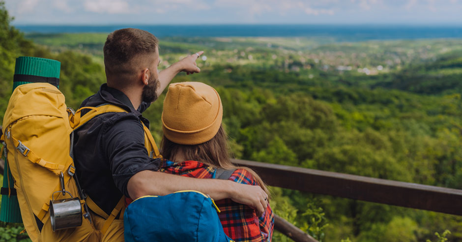 dvojica turistov oblečená v športovom oblečení pozoruje v objatí výhľad na prírodu